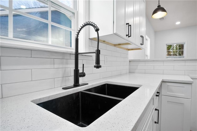 kitchen featuring backsplash, white cabinetry, and sink