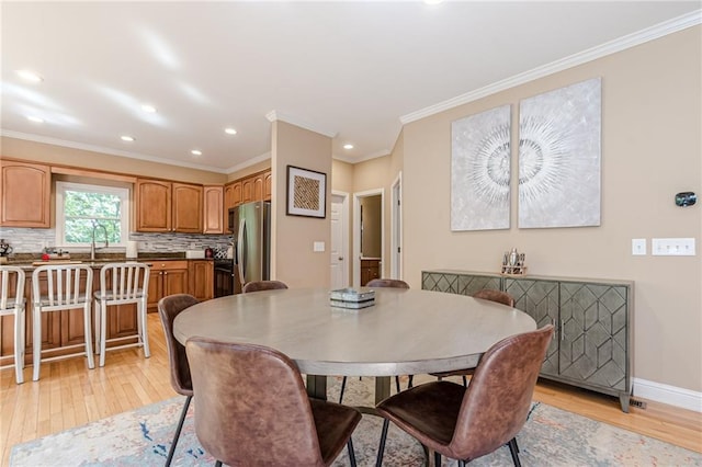 dining room featuring light hardwood / wood-style floors, crown molding, and sink