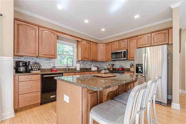 kitchen featuring a breakfast bar area, black appliances, stone countertops, light hardwood / wood-style floors, and a center island