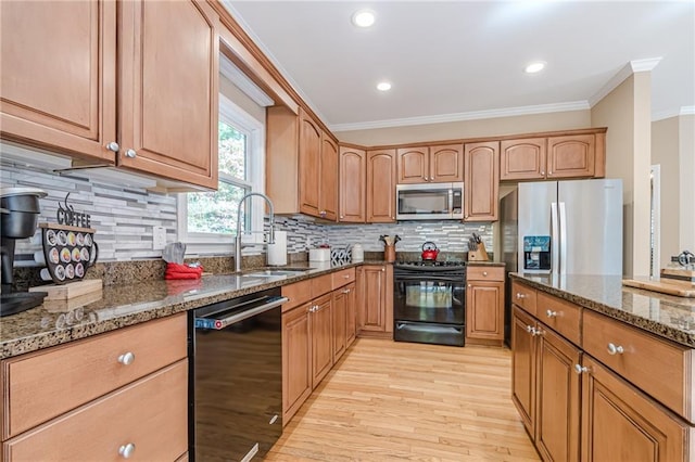 kitchen with black appliances, sink, light wood-type flooring, dark stone countertops, and crown molding