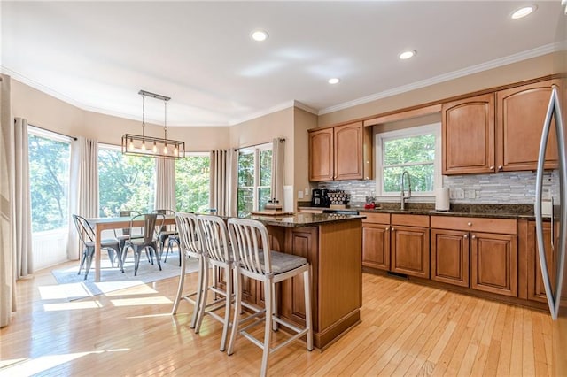 kitchen featuring light wood-type flooring, plenty of natural light, a kitchen island, and hanging light fixtures