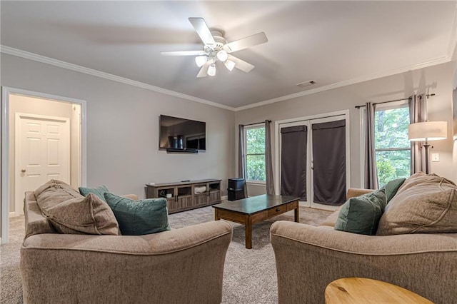 carpeted living room with a wealth of natural light, ornamental molding, and ceiling fan