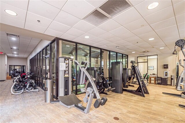 exercise room with hardwood / wood-style floors and a paneled ceiling