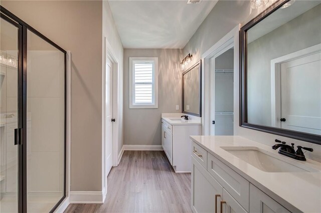 361 Creek Wood Park Dr, Ball Ground, GA 30107 - bathroom featuring a shower stall, wood finished floors, two vanities, and baseboards