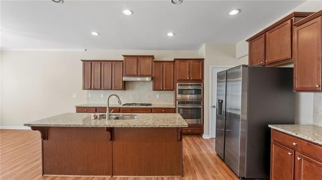 705 Ayala Pl, Alpharetta, GA 30004 - kitchen with decorative backsplash, under cabinet range hood, a sink, light wood finished floors, and stainless steel appliances
