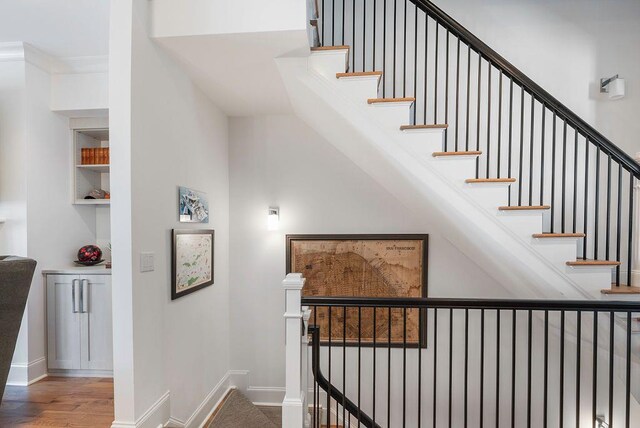 stairs with crown molding and hardwood / wood-style flooring