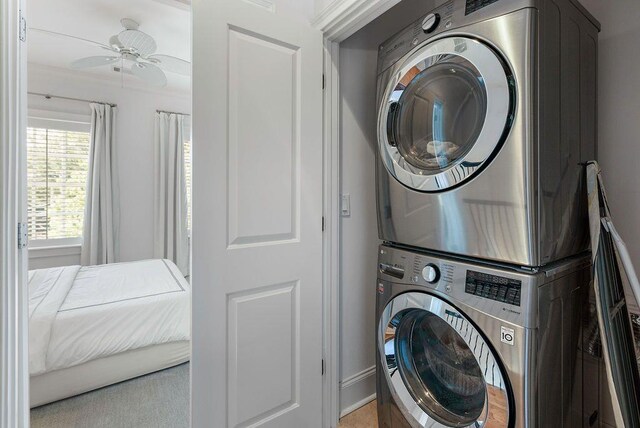 laundry area featuring ceiling fan, light colored carpet, and stacked washer and clothes dryer