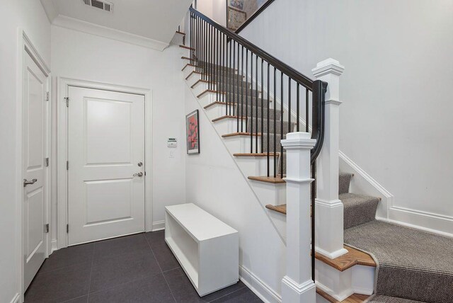 stairs featuring tile patterned floors and ornamental molding