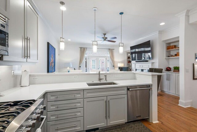 kitchen featuring hardwood / wood-style floors, stainless steel appliances, sink, kitchen peninsula, and ceiling fan