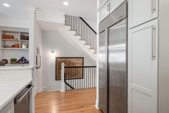 stairs featuring ornamental molding, wine cooler, and hardwood / wood-style flooring