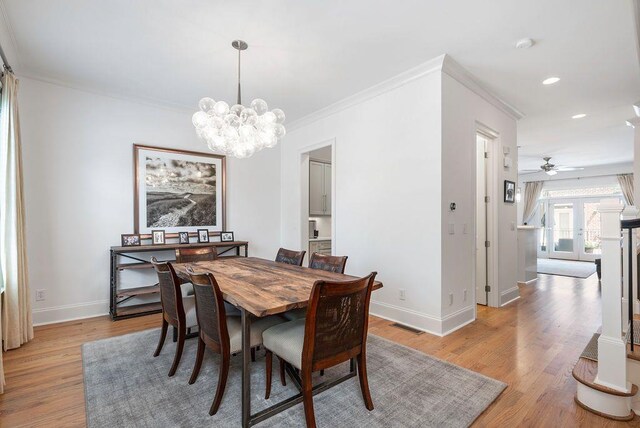 dining space with ornamental molding, ceiling fan with notable chandelier, and light hardwood / wood-style floors