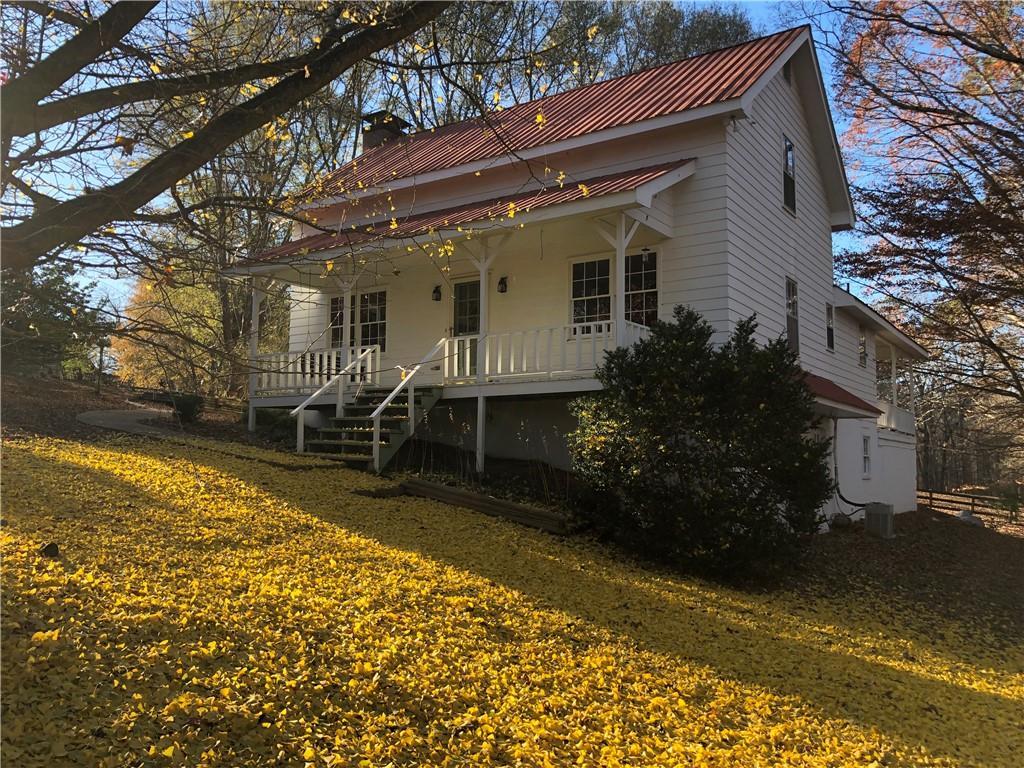 view of front of house with central AC unit, covered porch, and a front yard