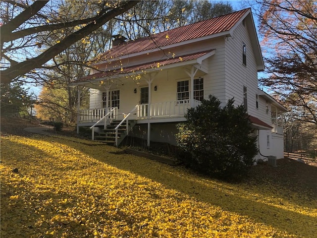 view of front of house with central AC unit, covered porch, and a front yard