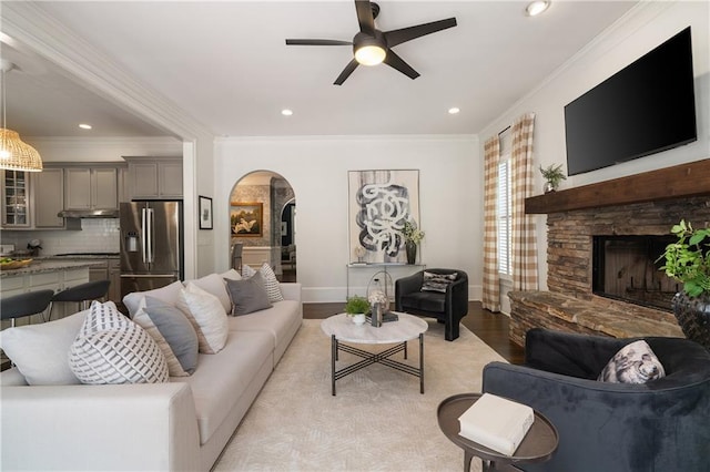 1003 N Ave NE, Atlanta, GA 30306 - living area featuring arched walkways, ceiling fan, a stone fireplace, light wood finished floors, and ornamental molding
