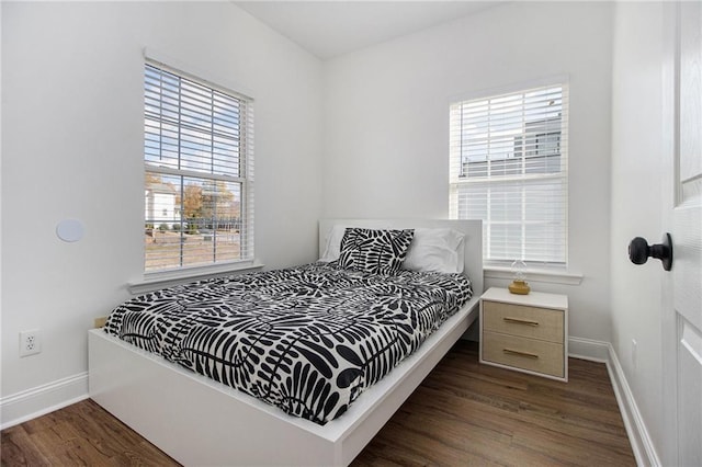 bedroom with dark wood-style floors and baseboards