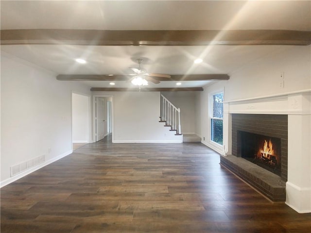 unfurnished living room with beam ceiling, ceiling fan, dark hardwood / wood-style flooring, and a brick fireplace