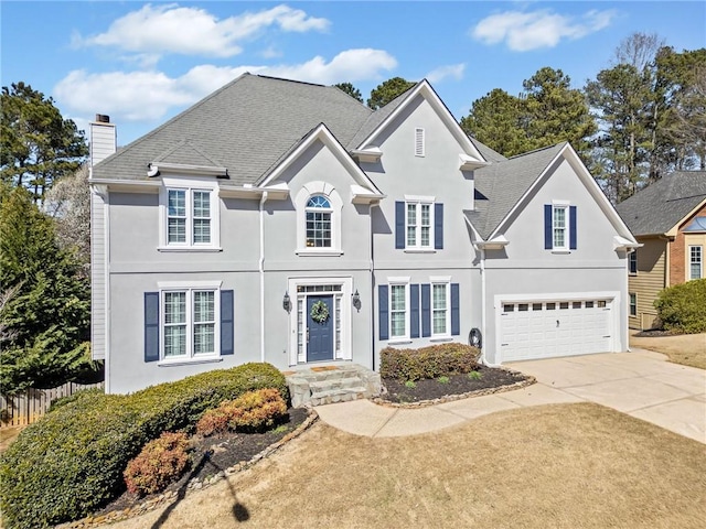 view of front of property featuring driveway, a garage, a chimney, fence, and stucco siding