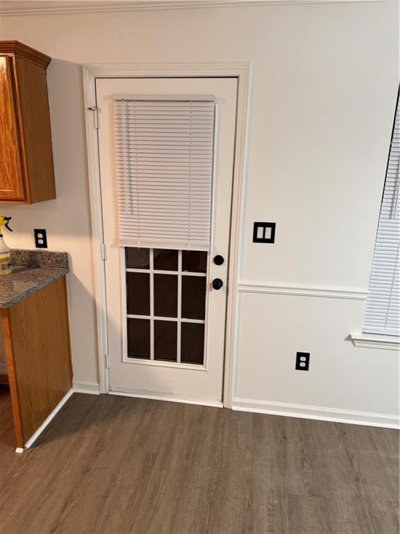 doorway featuring baseboards and dark wood-style floors