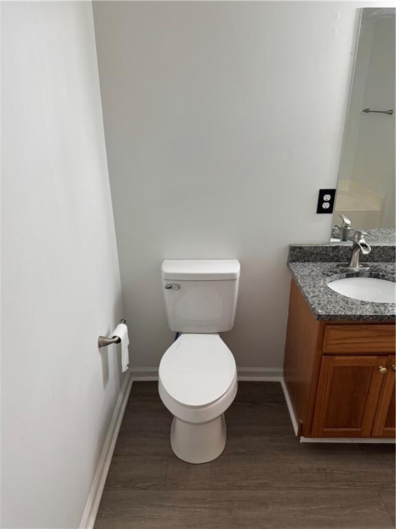 bathroom with toilet, baseboards, wood finished floors, and vanity