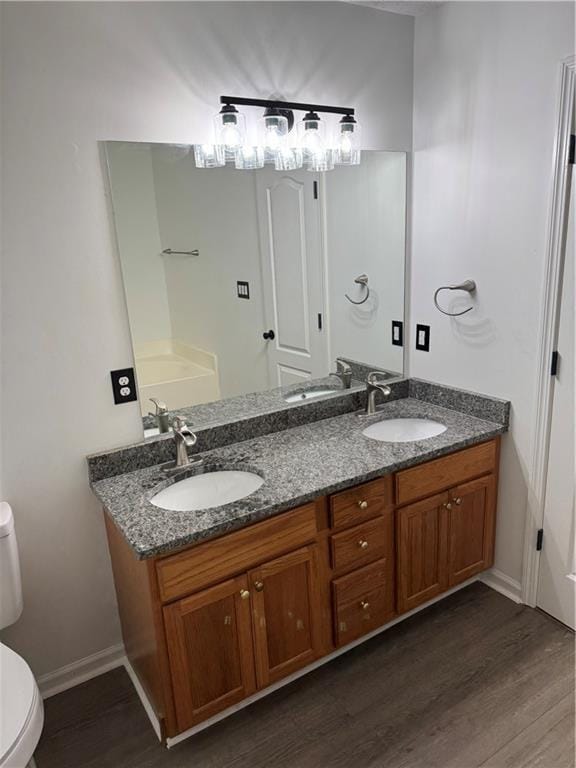 full bathroom with double vanity, toilet, a sink, and wood finished floors