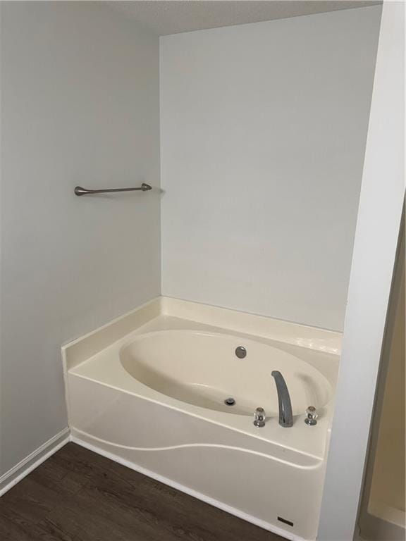 bathroom featuring baseboards, wood finished floors, and a garden tub