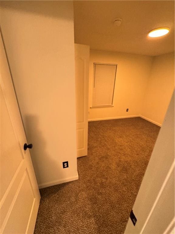 unfurnished room featuring baseboards and dark carpet