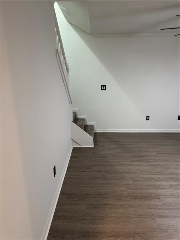 unfurnished room with baseboards, dark wood-style flooring, and stairway