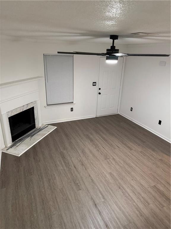 unfurnished living room with a textured ceiling, a ceiling fan, baseboards, wood finished floors, and a high end fireplace