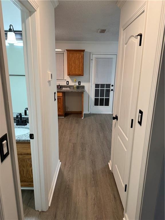 hallway featuring visible vents, ornamental molding, dark wood-style flooring, baseboards, and a textured ceiling