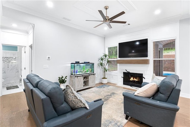 living room with a fireplace, light wood-type flooring, ceiling fan, and a healthy amount of sunlight