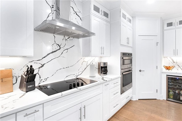 kitchen featuring white cabinets, black electric stovetop, beverage cooler, and wall chimney exhaust hood