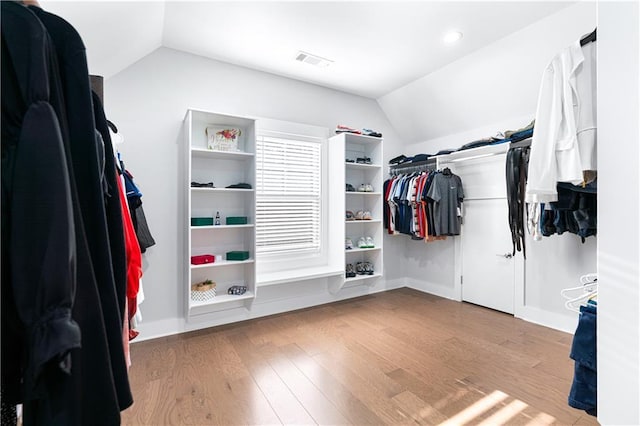 spacious closet with light hardwood / wood-style floors and vaulted ceiling