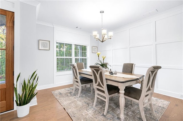 dining area with an inviting chandelier, ornamental molding, and light hardwood / wood-style floors