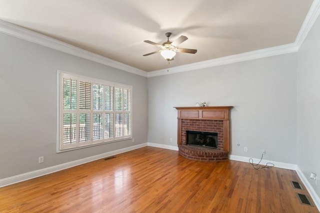 unfurnished living room with crown molding, a brick fireplace, wood-type flooring, and ceiling fan