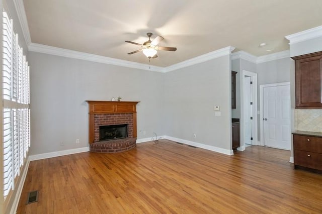 unfurnished living room featuring crown molding, light hardwood / wood-style flooring, a brick fireplace, and ceiling fan