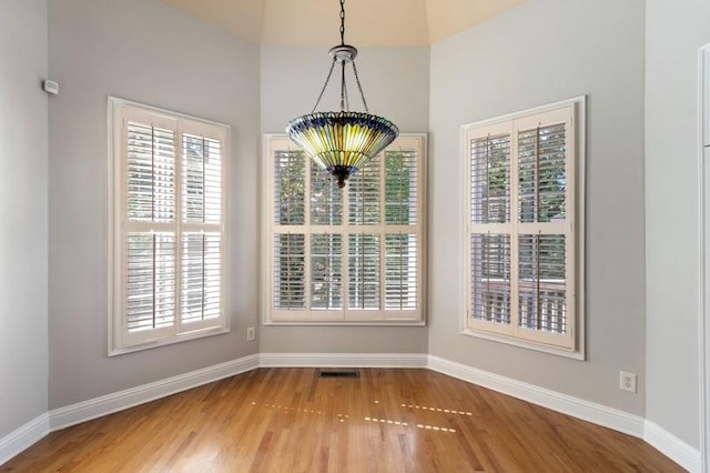 unfurnished dining area featuring a chandelier and hardwood / wood-style flooring