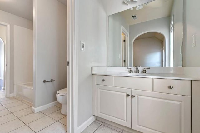 bathroom featuring toilet, vanity, tile patterned floors, and a bath