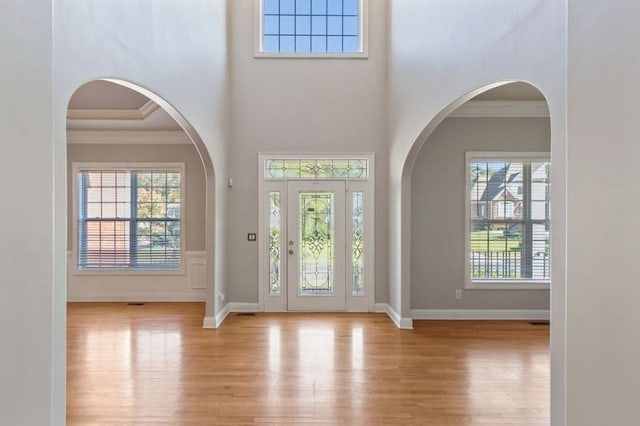 entryway featuring ornamental molding, light wood-type flooring, and a wealth of natural light