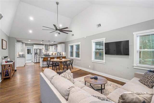 living room featuring vaulted ceiling, wood-type flooring, and ceiling fan