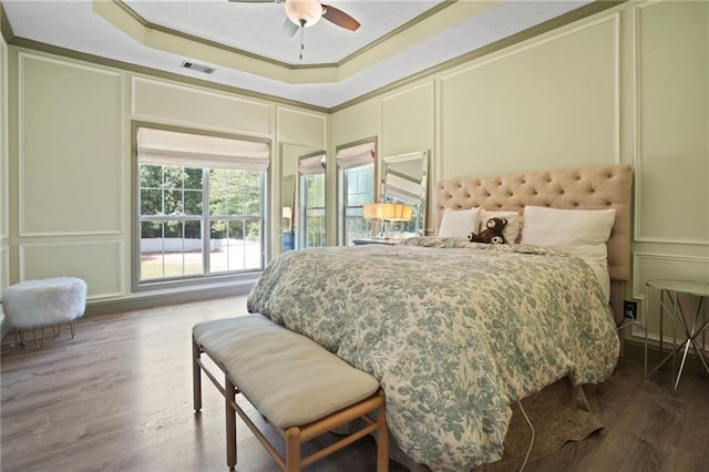 bedroom featuring ceiling fan, ornamental molding, a tray ceiling, and dark hardwood / wood-style flooring