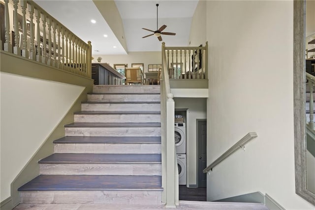 stairs featuring hardwood / wood-style flooring, stacked washer and clothes dryer, ceiling fan, and a high ceiling