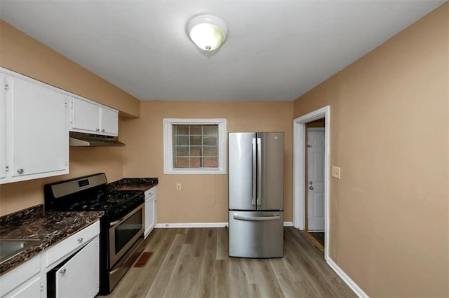 kitchen with dark stone countertops, stainless steel appliances, light wood-type flooring, and white cabinets