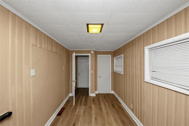 corridor with ornamental molding and light hardwood / wood-style flooring