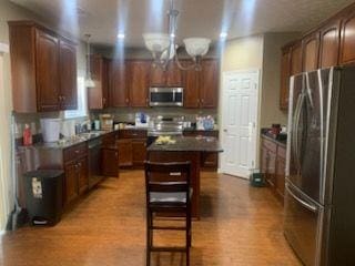 9590 English Ivy Ct, Fortson, GA 31808 - kitchen with a kitchen island, pendant lighting, dark countertops, appliances with stainless steel finishes, and wood finished floors