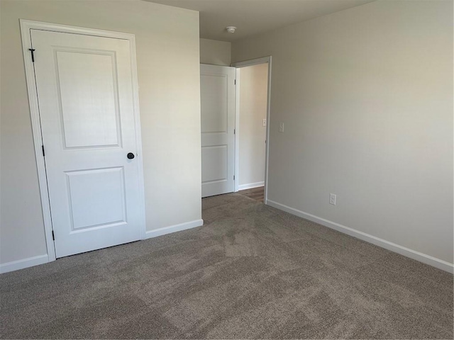 unfurnished bedroom featuring a closet and dark carpet