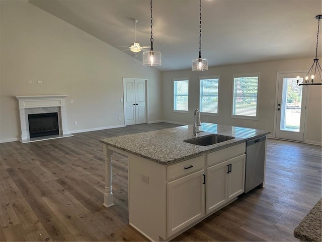 kitchen featuring dark hardwood / wood-style flooring, white cabinetry, a kitchen island with sink, stainless steel dishwasher, and light stone counters