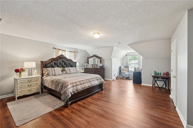 bedroom with wood finished floors, a textured ceiling, baseboards, and vaulted ceiling