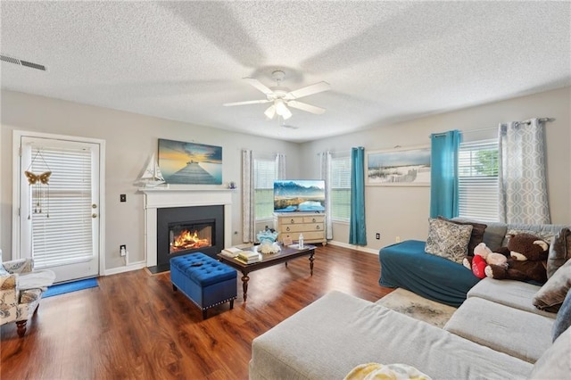 living room with a ceiling fan, a fireplace with flush hearth, wood finished floors, a textured ceiling, and baseboards