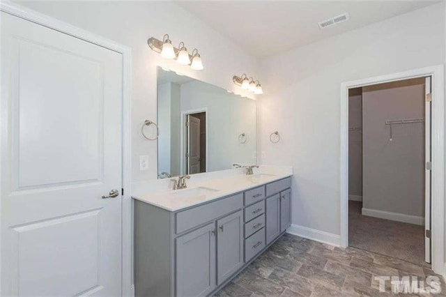 251 Eason St, Bowdon, GA 30108 - bathroom with double vanity, a walk in closet, baseboards, and stone finish floors