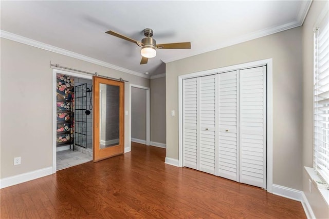 unfurnished bedroom featuring crown molding, a closet, baseboards, and wood finished floors